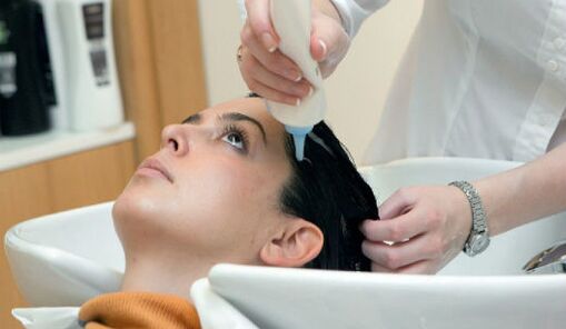 Le maître applique le produit au fur et à mesure qu'il passe dans les cheveux